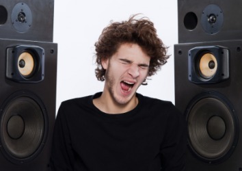 A young man sings while his stereo blares. A young man sings while his stereo blares.