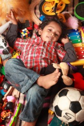 A child lays in a jumble of toys. A child lays in a jumble of toys.