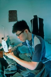 A young man sewing with a sewing machine. A young man sewing with a sewing machine.