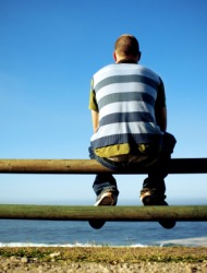 A man sits on a fence. A man sits on a fence.