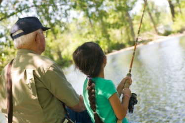A grandfather imparts his knowledge of fishing to his granddaughter. A grandfather imparts his knowledge of fishing to his granddaughter.