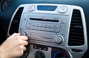 A person adjusts the volume on their car radio. A person adjusts the volume on their car radio.
