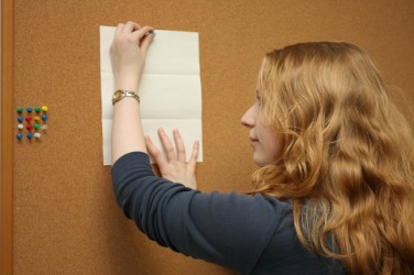 A woman places a notice on a bulletin board. A woman places a notice on a bulletin board.