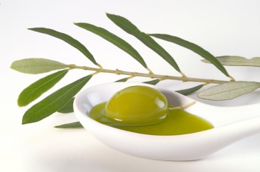 An olive rests in a spoon of extra-virgin olive oil. An olive rests in a spoon of extra-virgin olive oil.
