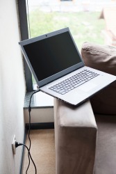 A laptop plugged into a wall. A laptop plugged into a wall.