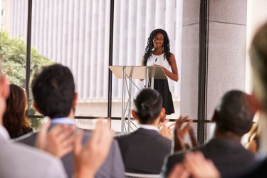 A speaker giving a presentation while standing on a podium. A speaker giving a presentation while standing on a podium.
