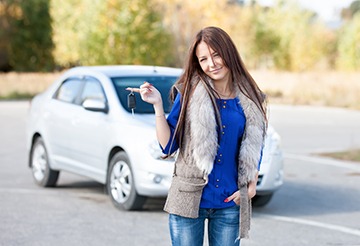 A young lady standing in front of her pre owned car. A young lady standing in front of her pre owned car.