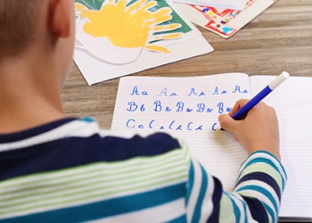 A school boy writing in print, practicing the alphabet. A school boy writing in print, practicing the alphabet.