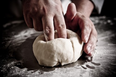A person prodding dough with their fingers. A person prodding dough with their fingers.