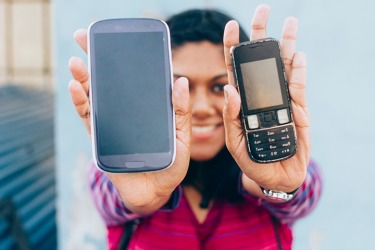 A woman shows the progress of an old cell phone versus a new smart phone. A woman shows the progress of an old cell phone versus a new smart phone.