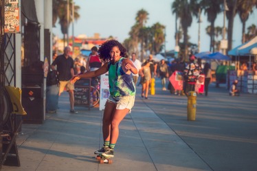 A young woman skateboarding on the promenade of the Venice Beach boardwalk. A young woman skateboarding on the promenade of the Venice Beach boardwalk.