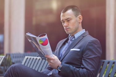 A businessman is reading a magazine publication. A businessman is reading a magazine publication.