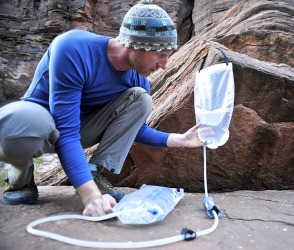 He uses a device to purify water in order to make it safe to drink while hiking in remote areas. He uses a device to purify water in order to make it safe to drink while hiking in remote areas.