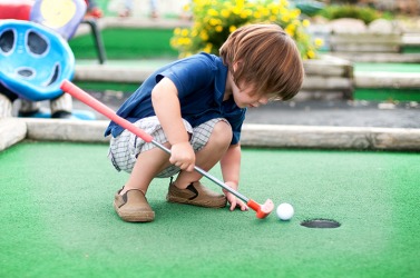 A young boy playing put put golf. A young boy playing put put golf.