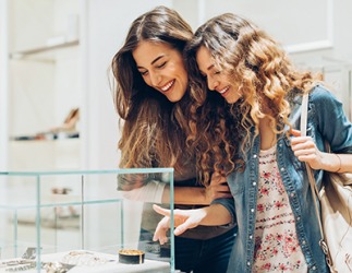 Julia and Chloe admire the jewelry in the showcase. Julia and Chloe admire the jewelry in the showcase.