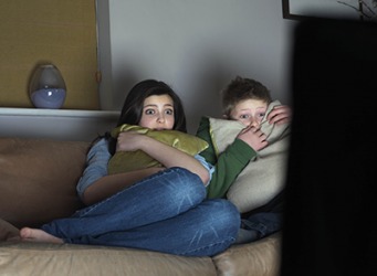Cassie and her brother shudder in fear as they watch the horror movie on TV. Cassie and her brother shudder in fear as they watch the horror movie on TV.