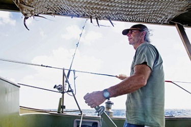 The skipper is steering his boat with the tiller. The skipper is steering his boat with the tiller.