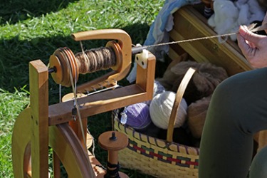 The woman slubs the lamb wool with the aid of a spinning wheel. The woman slubs the lamb wool with the aid of a spinning wheel.