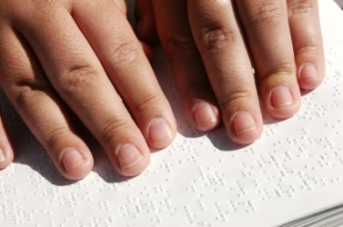 A person reading a book written in Braille. A person reading a book written in Braille.