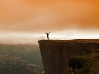 A hiker stands on top of a cliff. A hiker stands on top of a cliff.