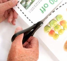 A person clipping a coupon from a paper. A person clipping a coupon from a paper.