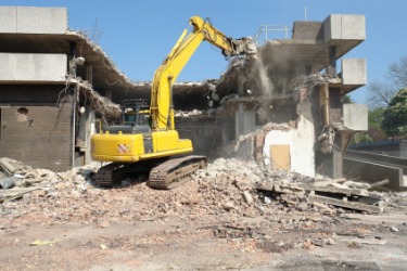 An excavator engaged in the destruction of a building. An excavator engaged in the destruction of a building.