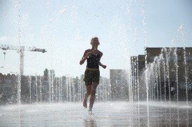 A girl getting drenched running through a fountain. A girl getting drenched running through a fountain.