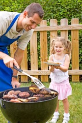 A man cooks food on a grill for his daughter. A man cooks food on a grill for his daughter.