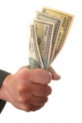 A hand grips money. A hand grips money.
