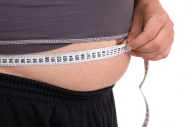 A man measures his gut. A man measures his gut.