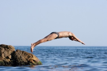A man jumps headfirst into the sea. A man jumps headfirst into the sea.