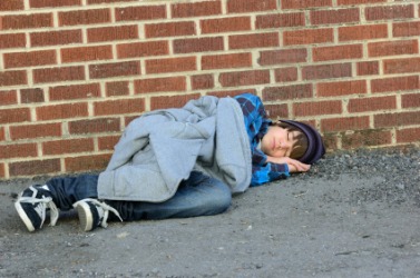 A homeless man asleep on the street. A homeless man asleep on the street.