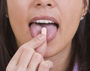 A woman about to ingest a pill. A woman about to ingest a pill.