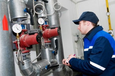 A heating inspector checks a boiler. A heating inspector checks a boiler.