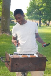 A young man cooking on a barbecue grill. A young man cooking on a barbecue grill.