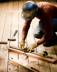 A man measures lumber for a deck. A man measures lumber for a deck.
