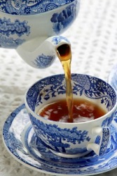 Tea pours from the spout of a teapot. Tea pours from the spout of a teapot.