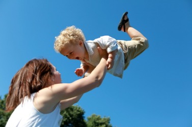A mother lifts her child into the air. A mother lifts her child into the air.