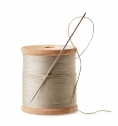 A sewing needle tucked into a spool of thread. A sewing needle tucked into a spool of thread.
