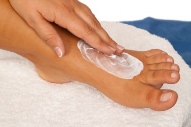 A person puts salve on their foot. A person puts salve on their foot.