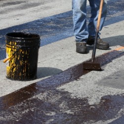 A man spreading hot tar on a road. A man spreading hot tar on a road.
