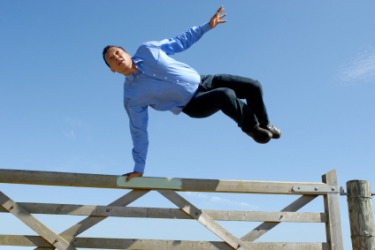 A man vaults over a gate. A man vaults over a gate.