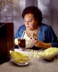 A woman binges on junk food and TV. A woman binges on junk food and TV.
