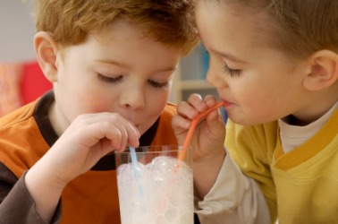 Two children bonding over a glass of milk. Two children bonding over a glass of milk.