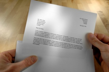 A person places a letter in an envelope. A person places a letter in an envelope.