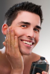 A young man applying after shave lotion. A young man applying after shave lotion.