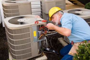 A repairman working on an air conditioner. A repairman working on an air conditioner.