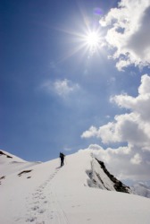 A hiker ascends a mountain ridge. A hiker ascends a mountain ridge.