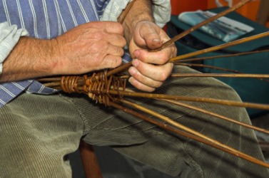 A man engaged in the craft of basketry. A man engaged in the craft of basketry.