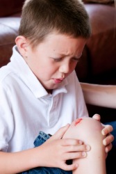 A boy has scraped his knee and made it bleed. A boy has scraped his knee and made it bleed.